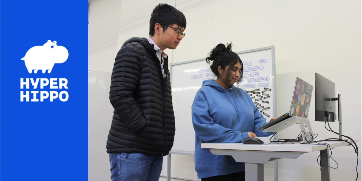 Two students looking at laptop on standing desk