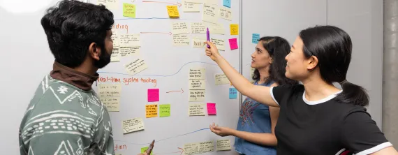 Students gathered around white board with sticky notes