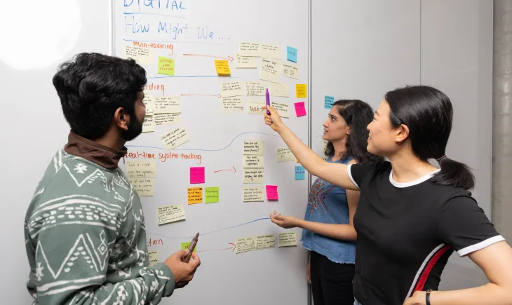 Students gathered around white board with sticky notes